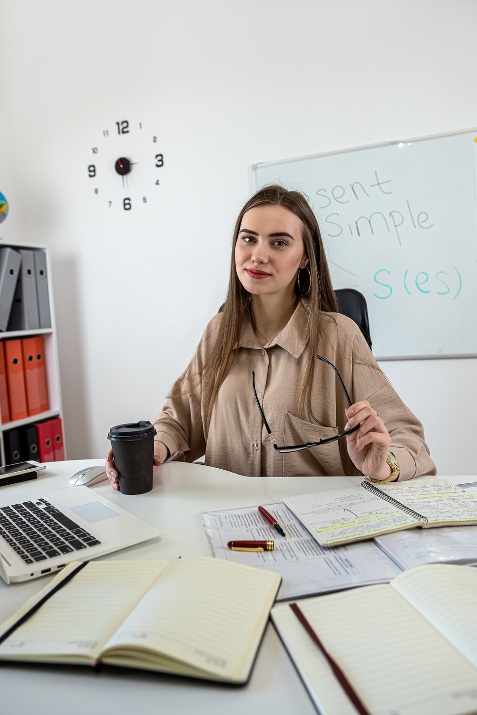 Young Teacher Sits at the Table and Explains English Grammar